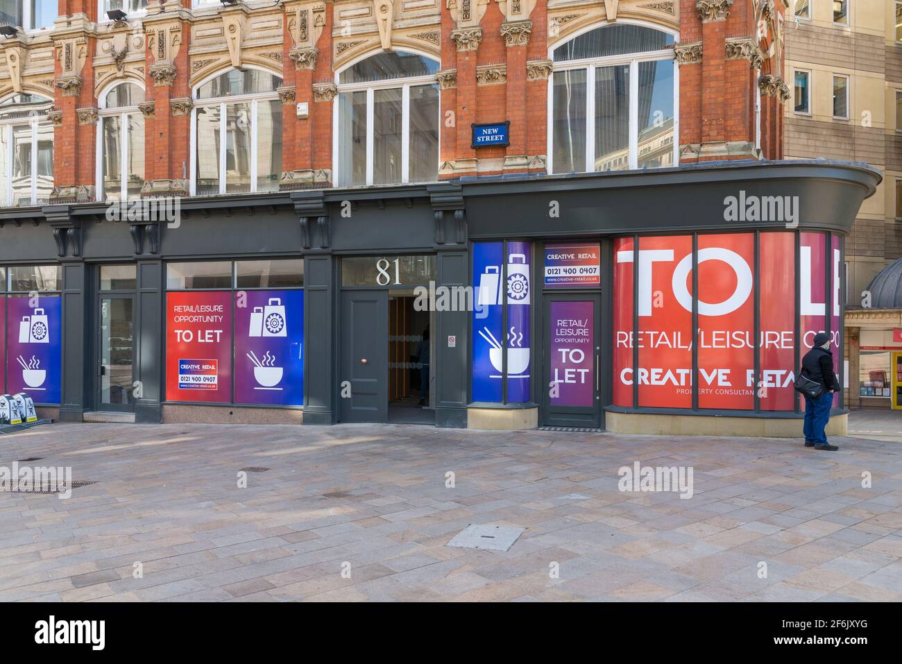 A closed down shop unit in New Street, Birmingham city centre with large signs say 'to let