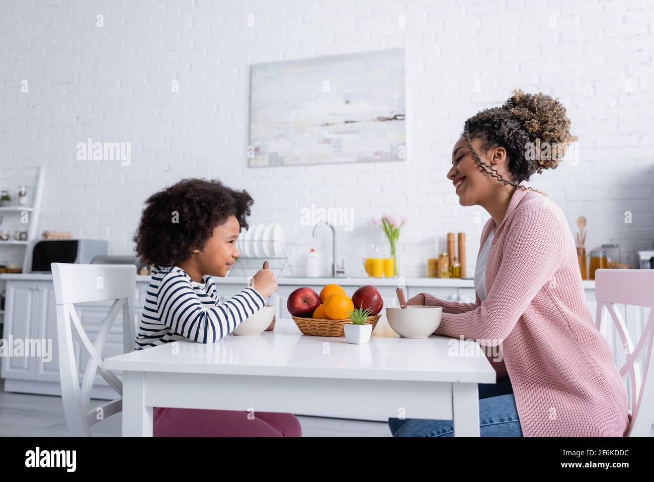 side view of african american mom and daughter looking at each other during breakfast Stock Photo