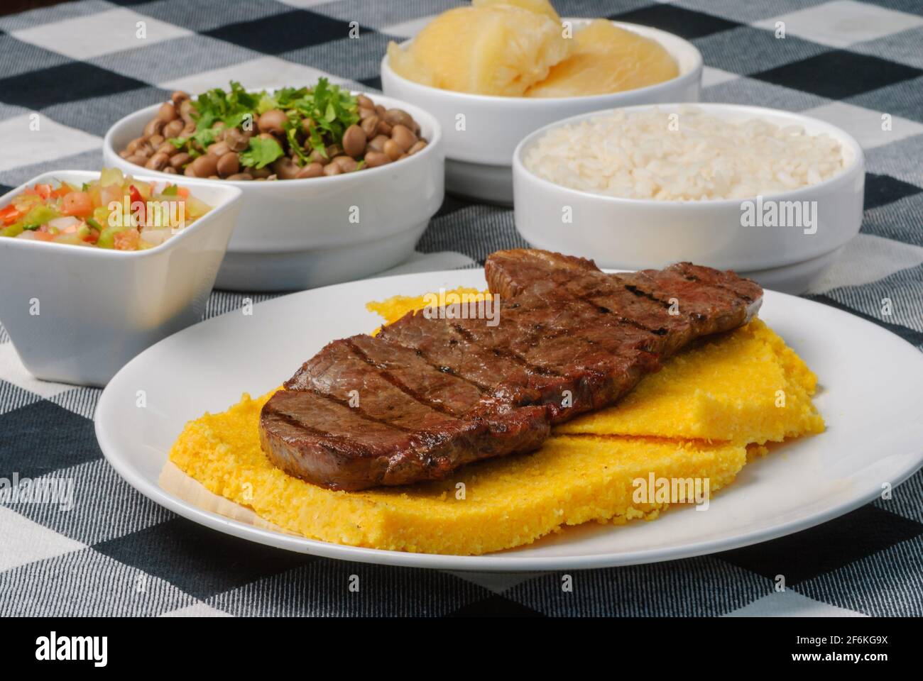Sun Meat With Brazilian Corn Couscous Accompanied With Rice Beans Manioc And Vinaigrette On A White Plate On Top Of A Black And White Checkered Ta Stock Photo Alamy