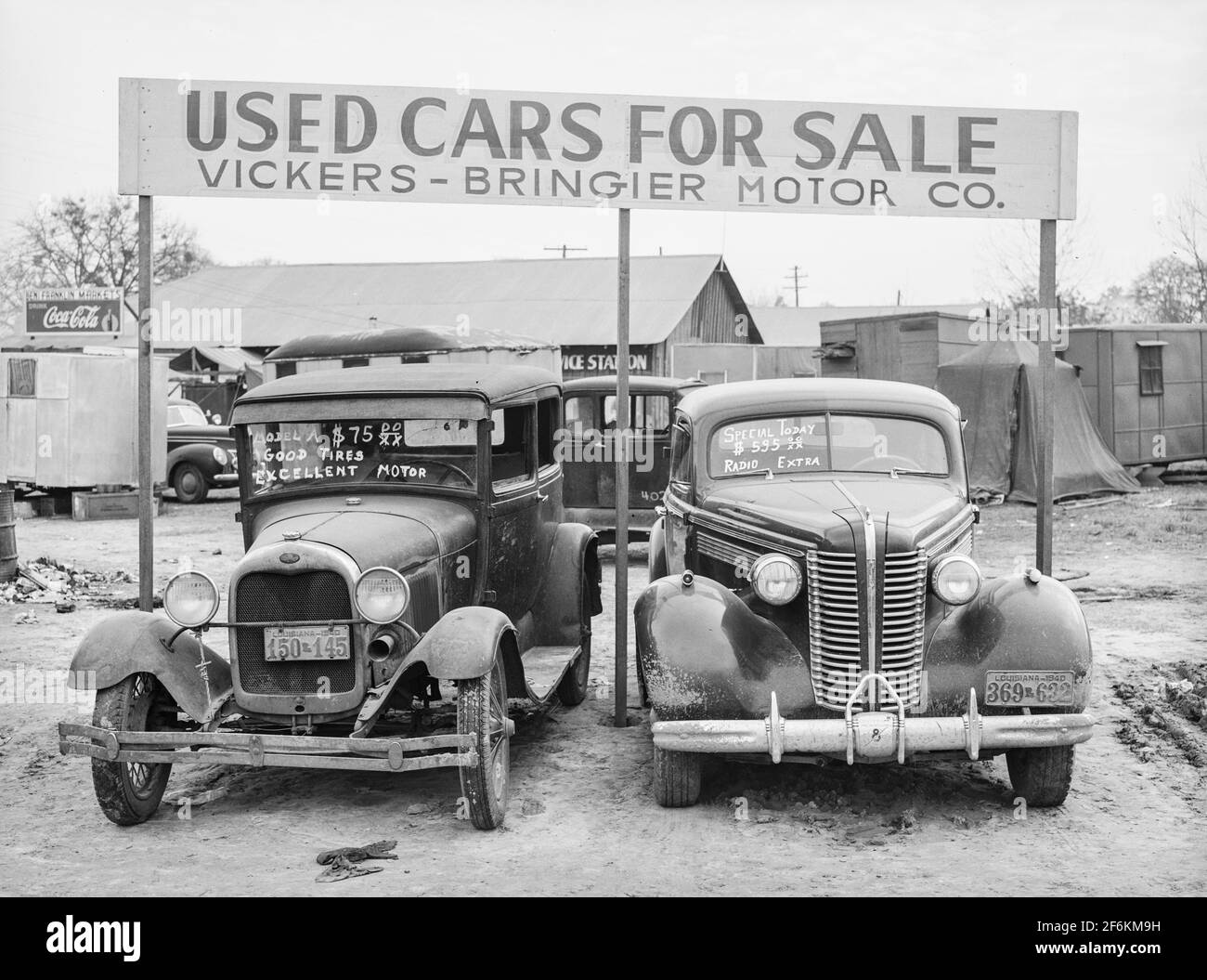 Used cars for sale with signs and prices at service station on main