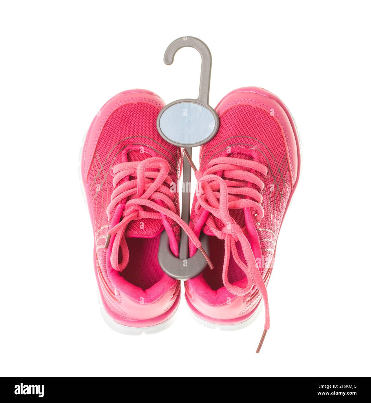 Pair of pink training shoes for girls on plastic hanger. Isolated on a