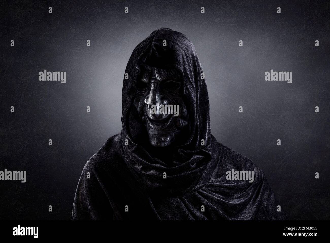 Scary witch in hooded cloak in the dark Stock Photo - Alamy