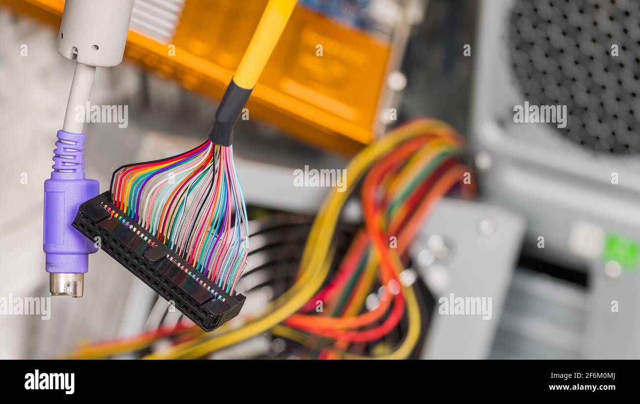 Colored hanging cables, connectors on e-waste heap background. Parallel multi wire or serial PS2 interface to computer storage device, keyboard, mouse. Stock Photo