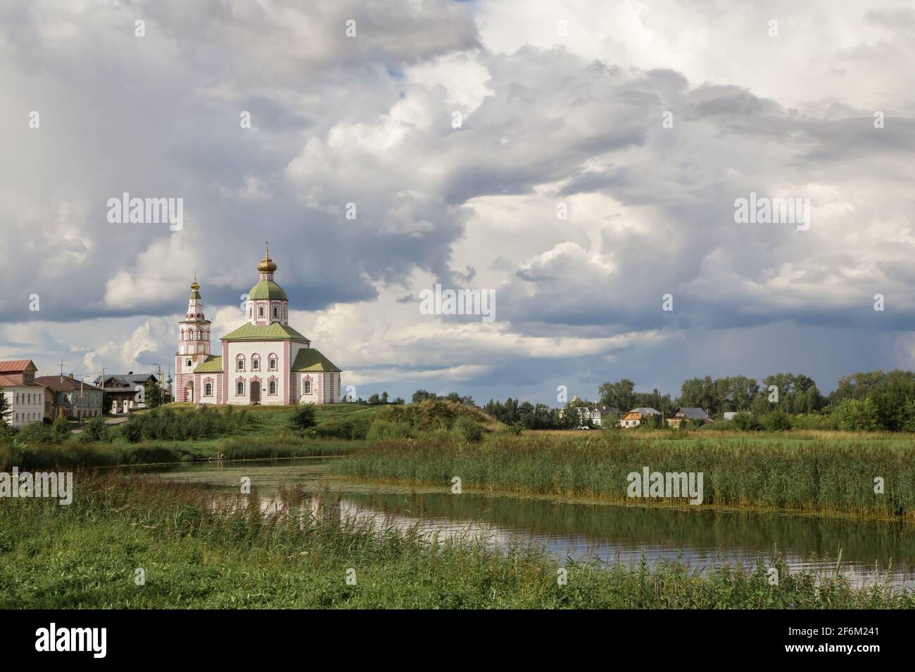 An old white-stone church on the bank of a small river. There are one ...