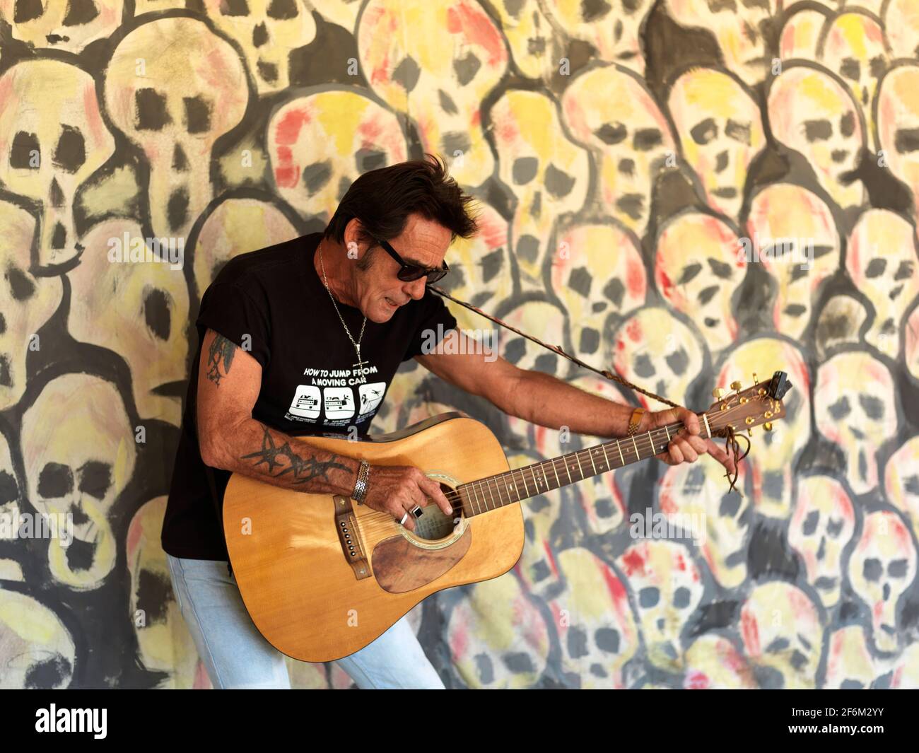 USA,Texas,Houston, portait of a rock guitar player against a background of painted skulls Stock Photo