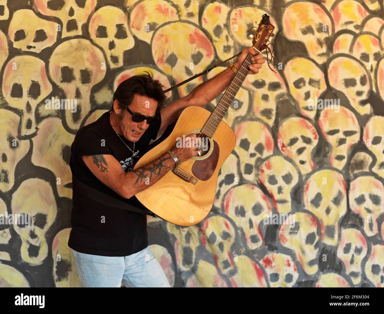 USA,Texas,Houston, portait of a rock guitar player against a background of painted skulls Stock Photo