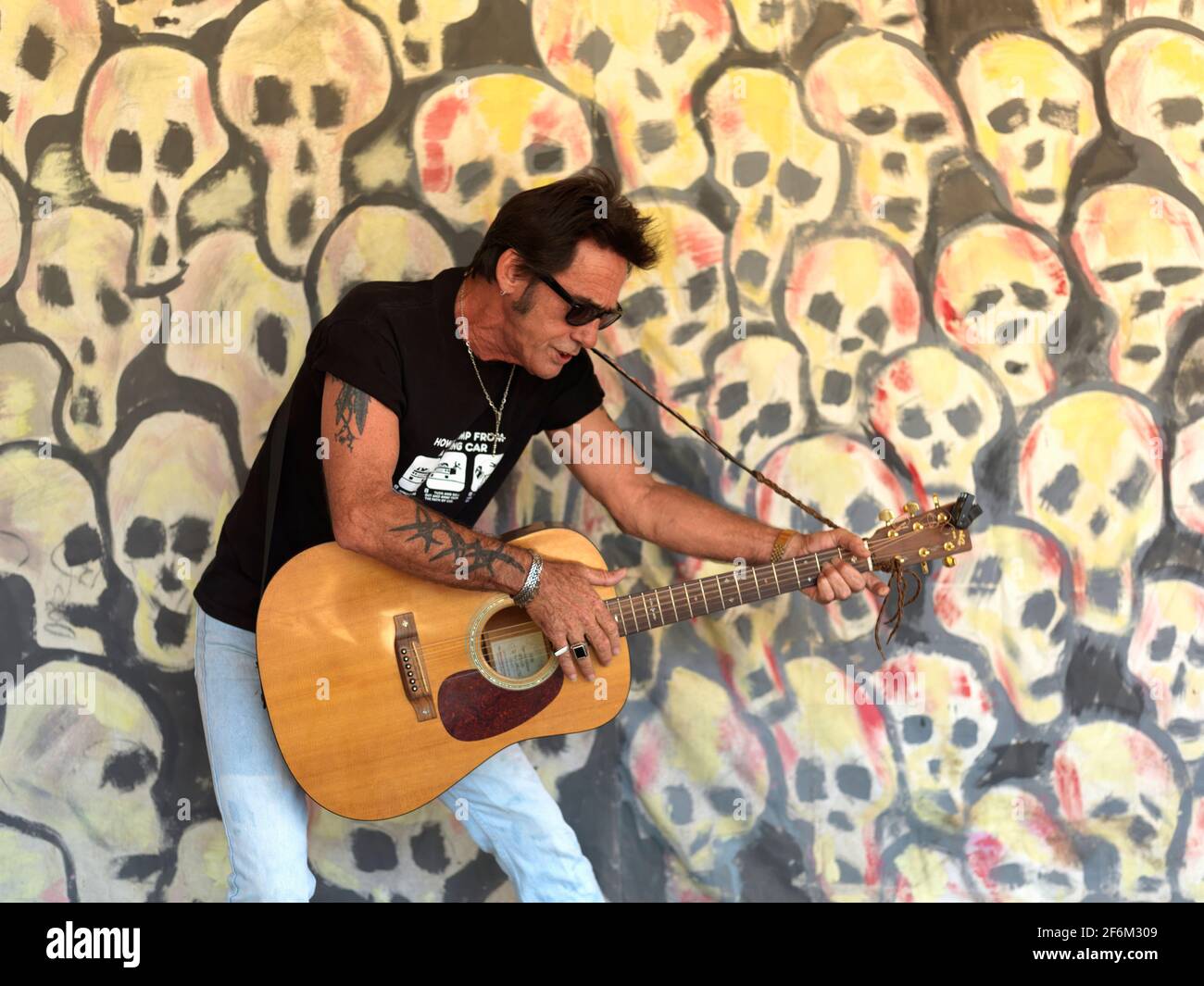 USA,Texas,Houston, portait of a rock guitar player against a background of painted skulls Stock Photo