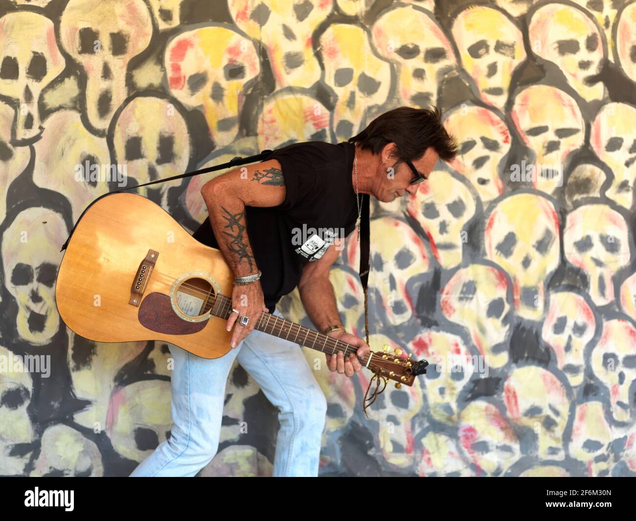 USA,Texas,Houston, portait of a rock guitar player against a background of painted skulls Stock Photo