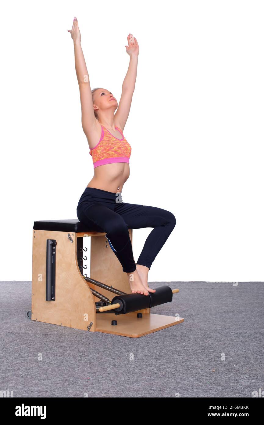 A 20-year-old trainer practices Pilates on an elevator chair, raising her  arms high above her head. Seated Stock Photo - Alamy