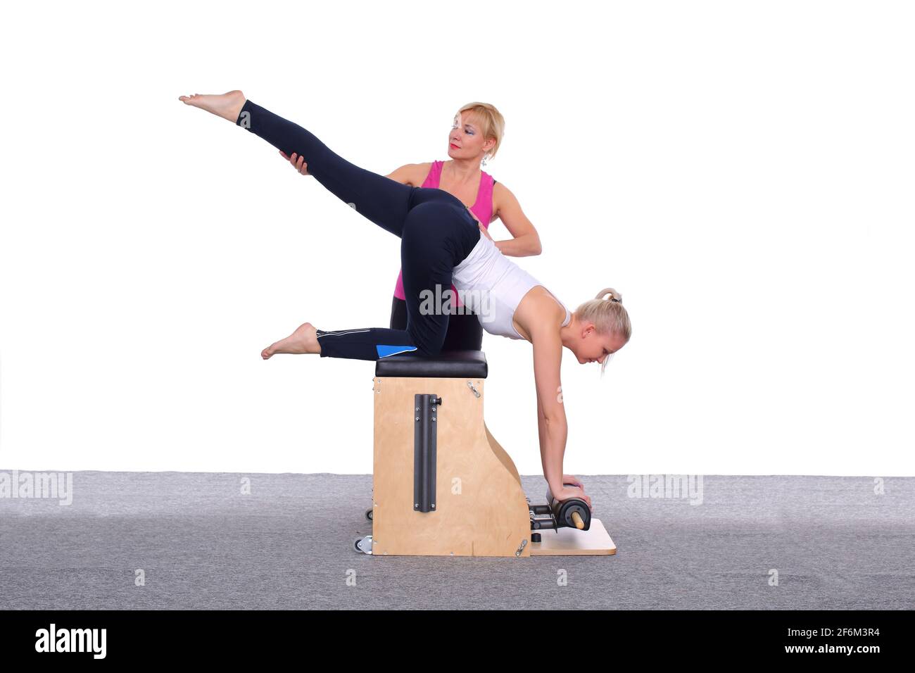 https://c8.alamy.com/comp/2F6M3R4/a-50-year-old-trainer-teaches-a-young-girl-to-practice-pilates-on-an-elevator-chair-by-lifting-her-leg-high-above-her-head-2F6M3R4.jpg