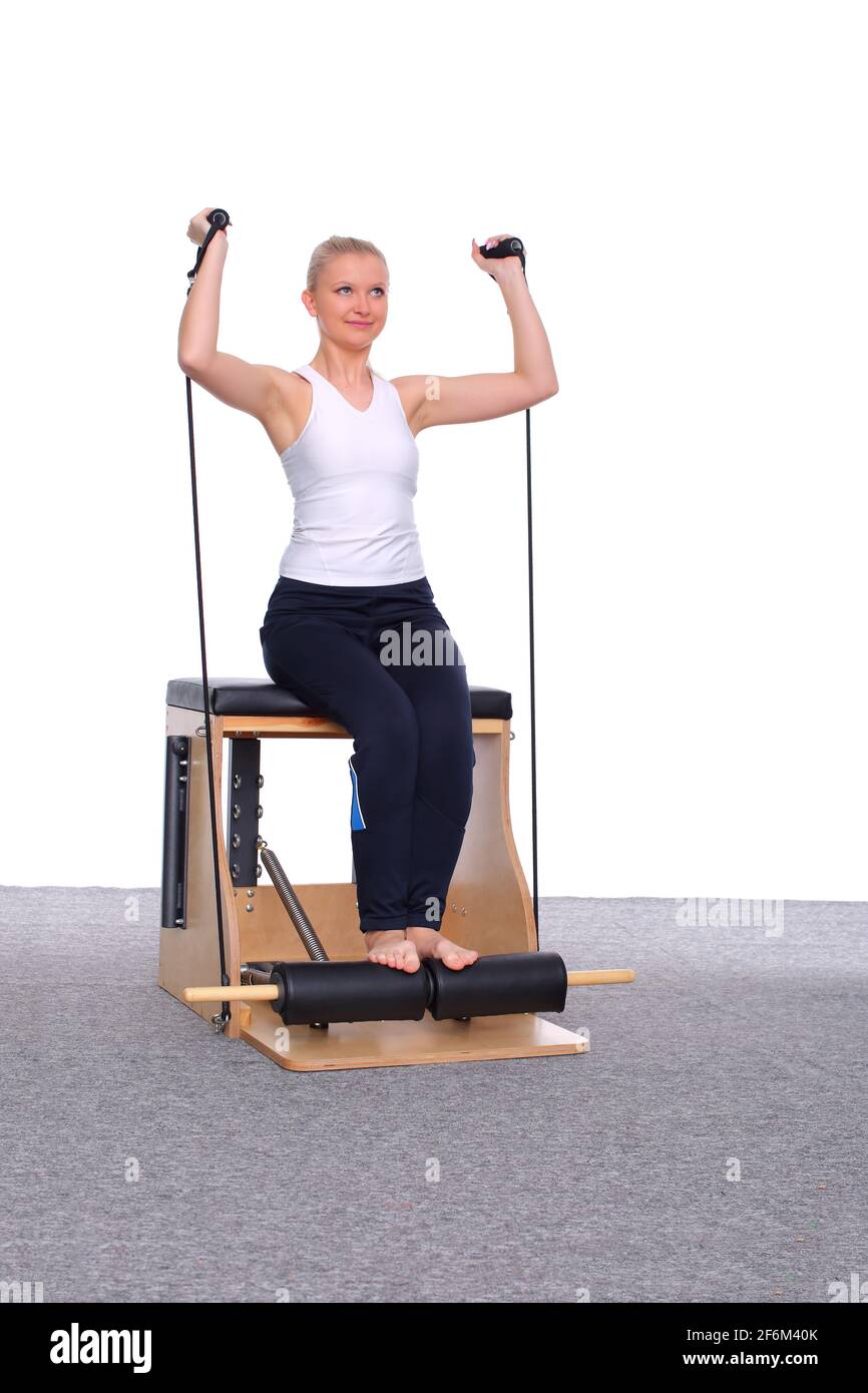 A 20-year-old trainer practices Pilates on an elevator chair with the help  of a gymnastics rubber band for her shoulder muscles Stock Photo - Alamy