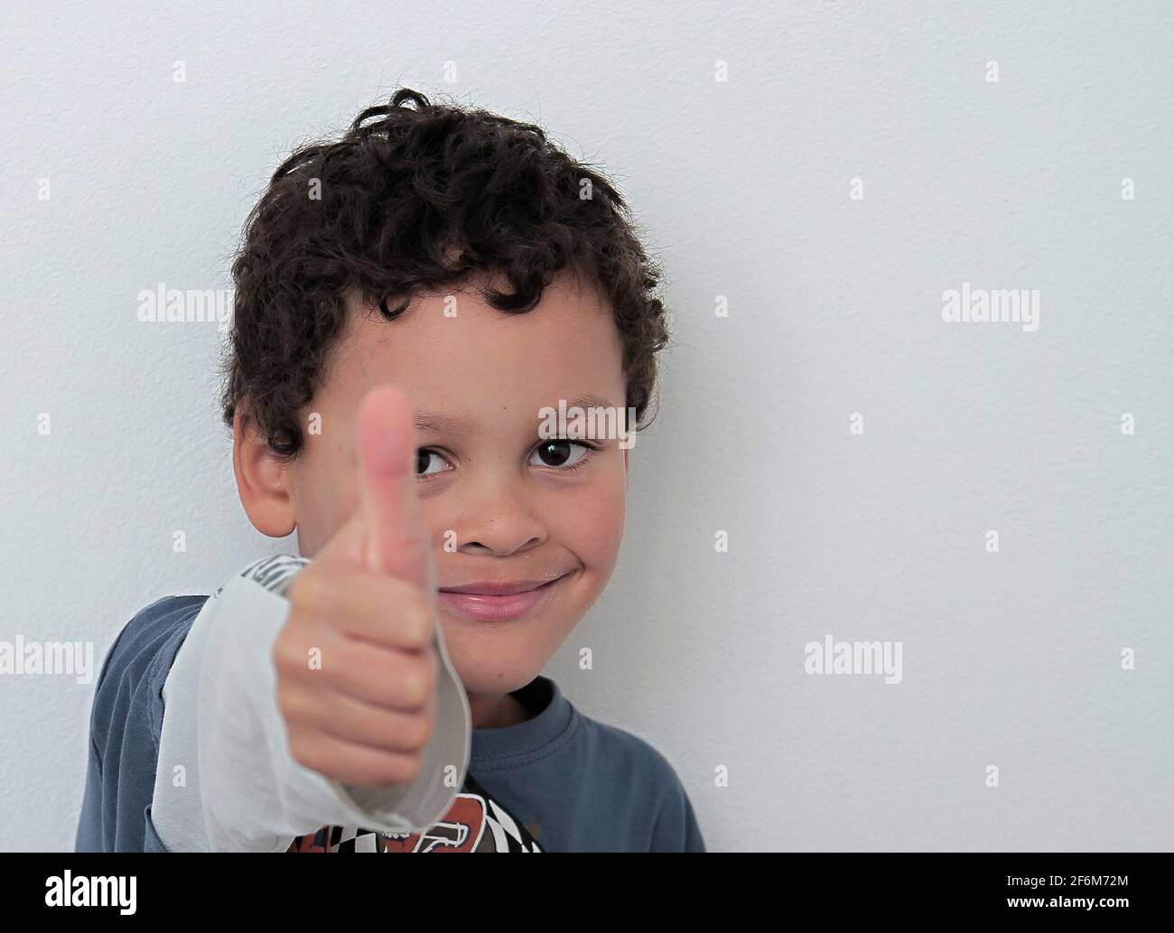 boy with thumbs up gesture on grey background stock photo Stock Photo