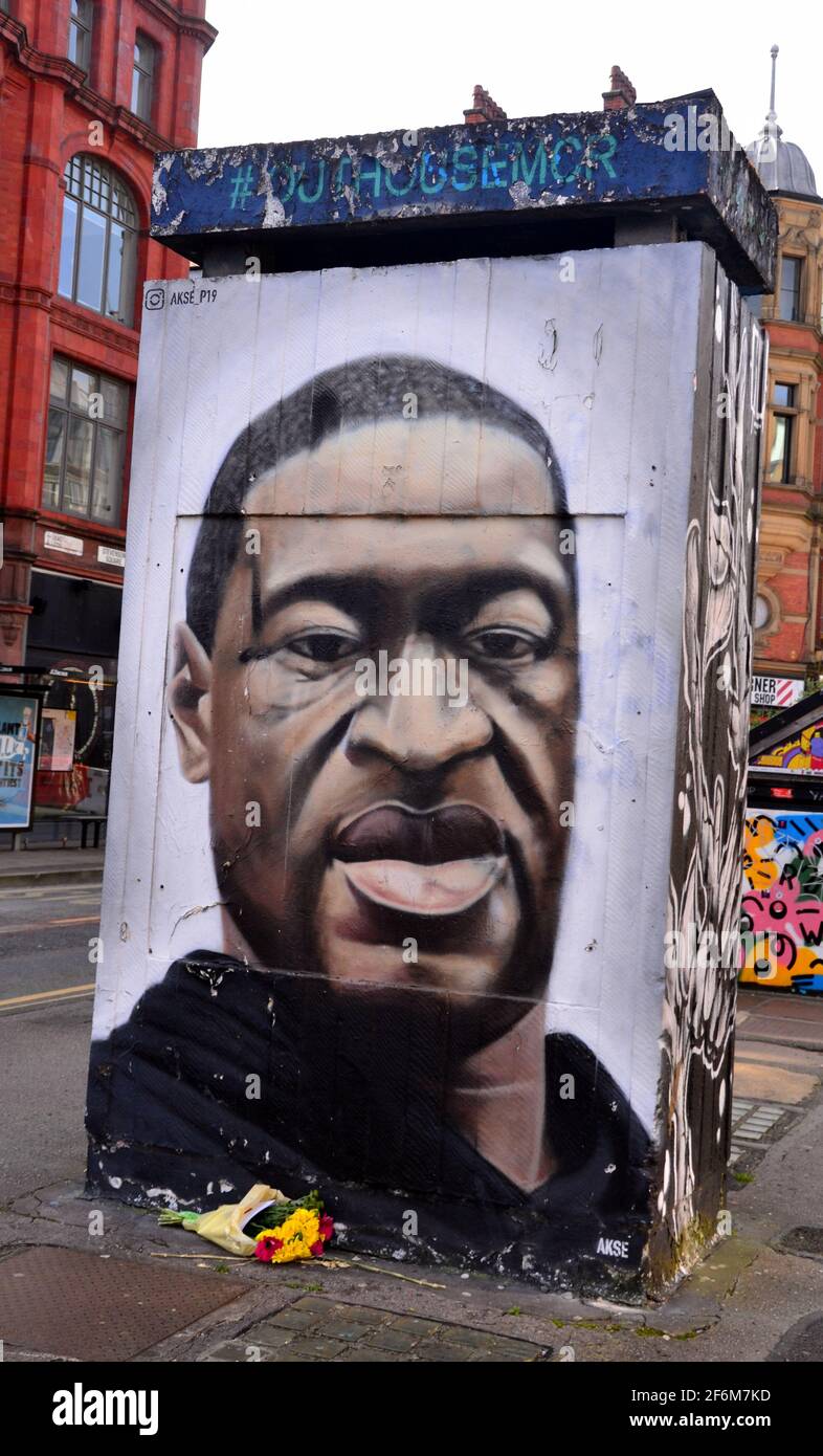 A bunch of flowers in front of a street art painting of George Floyd in  central Manchester, England, United Kingdom as the murder trial of former US police officer Derek Chauvin enters its fourth day in the USA. Mr Chauvin, 45, denies charges of murder and manslaughter. George Perry Floyd Jr. was an African American man who died on May 25, 2020 during an arrest after a store clerk alleged he had passed a counterfeit $20 bill in Minneapolis. Stock Photo