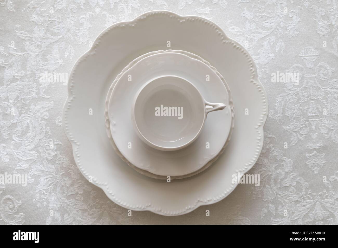 White Porcelain Place Setting Stacked on White Tablecloth Stock Photo