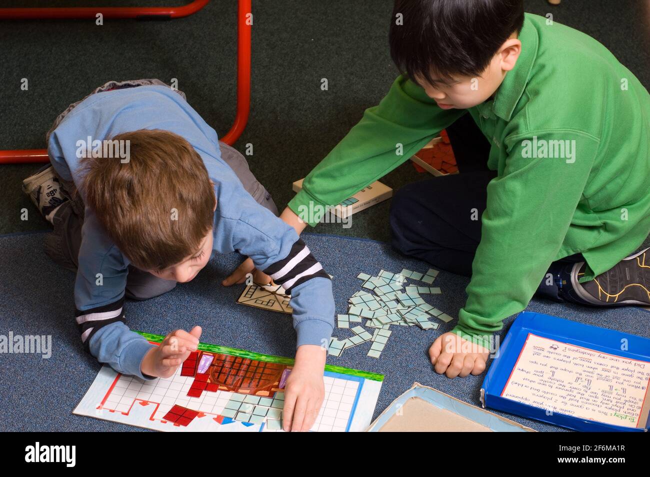 Independent elementary school Grade 4 and Kindergarten buddies older boy helping younger boy with learning activity Stock Photo