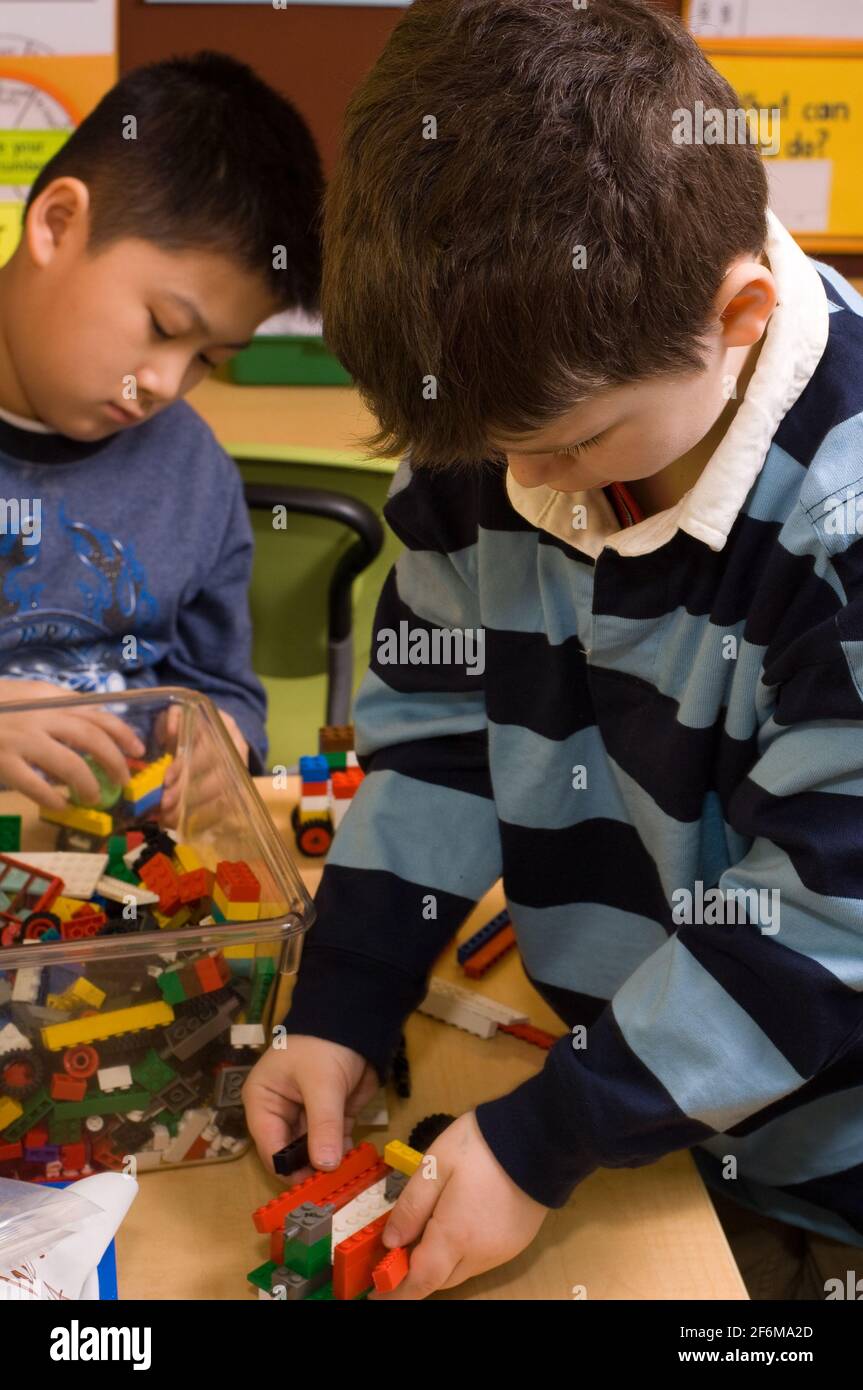Independent elementary school Grade 4 and Kindergarten buddies two boys building with legos Stock Photo