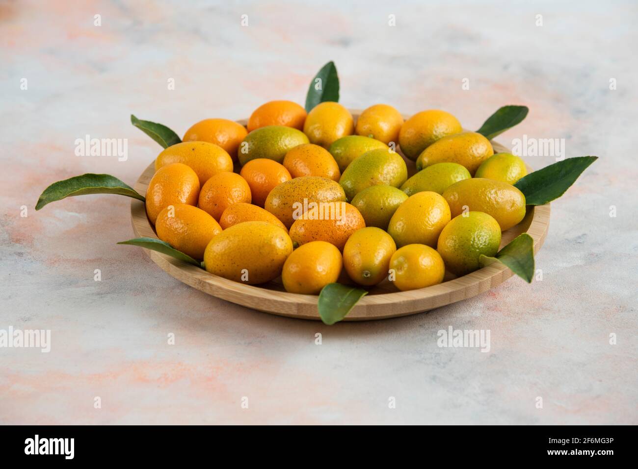 Close up photo, Pile of kumquats on wooden plate over colorful background Stock Photo