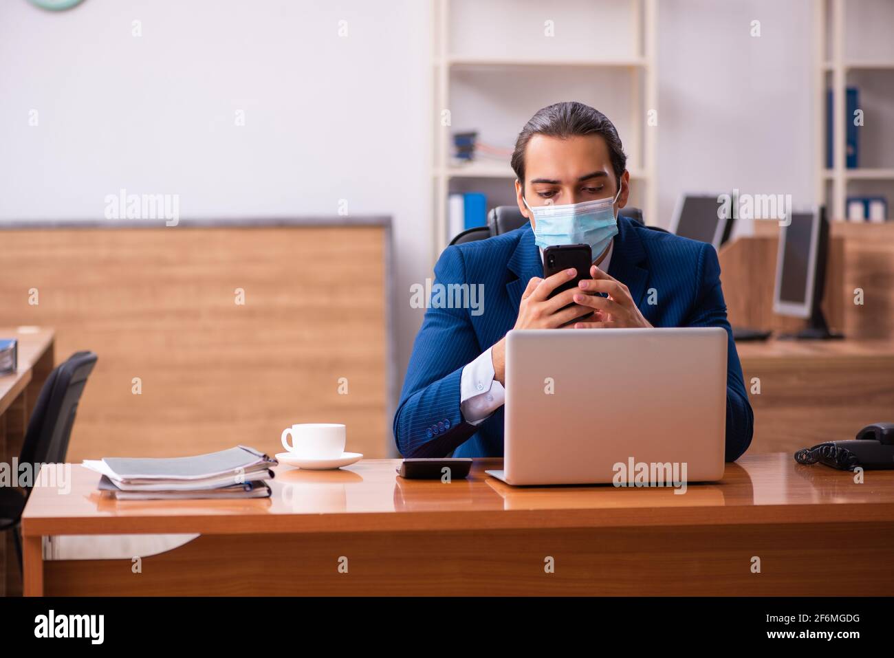 Young employee working in the office wearing mask Stock Photo - Alamy