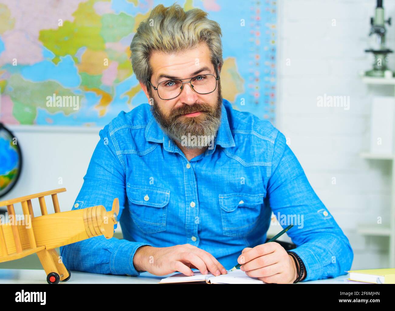 Exam in college. Professor working at table in classroom. Handsome male primary school teacher in classroom. Back to school. Stock Photo