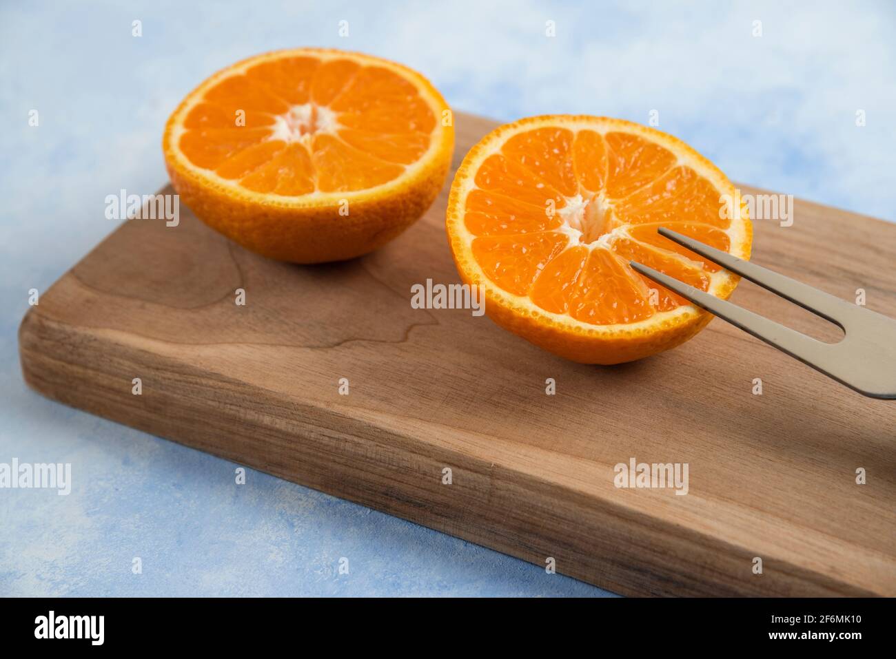 Close up photo of half cut clementine mandarin on wooden board Stock Photo