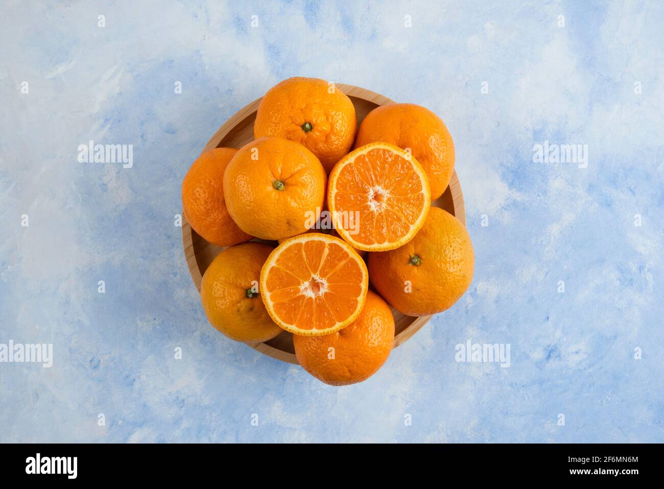 Top view. Pile of clementine mandarins on wooden plate over blue background Stock Photo