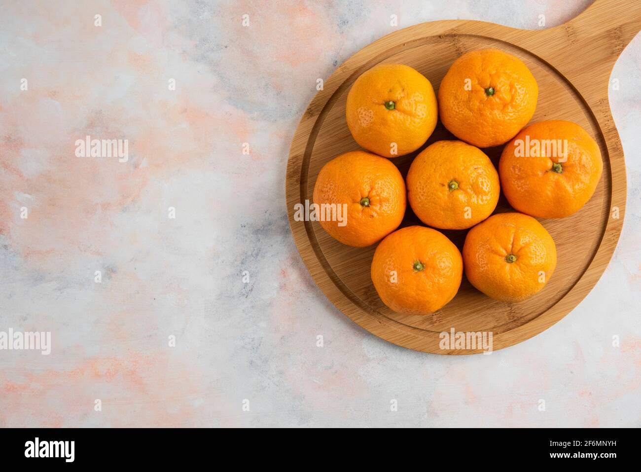Pile of clementine mandarins over wooden cutting board Stock Photo