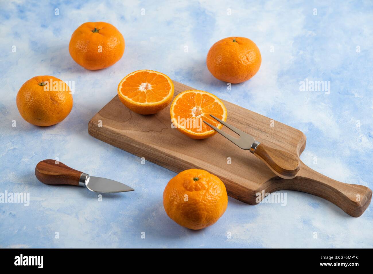 Pile of mandarins. Whole or half cut on wooden cutting board Stock Photo