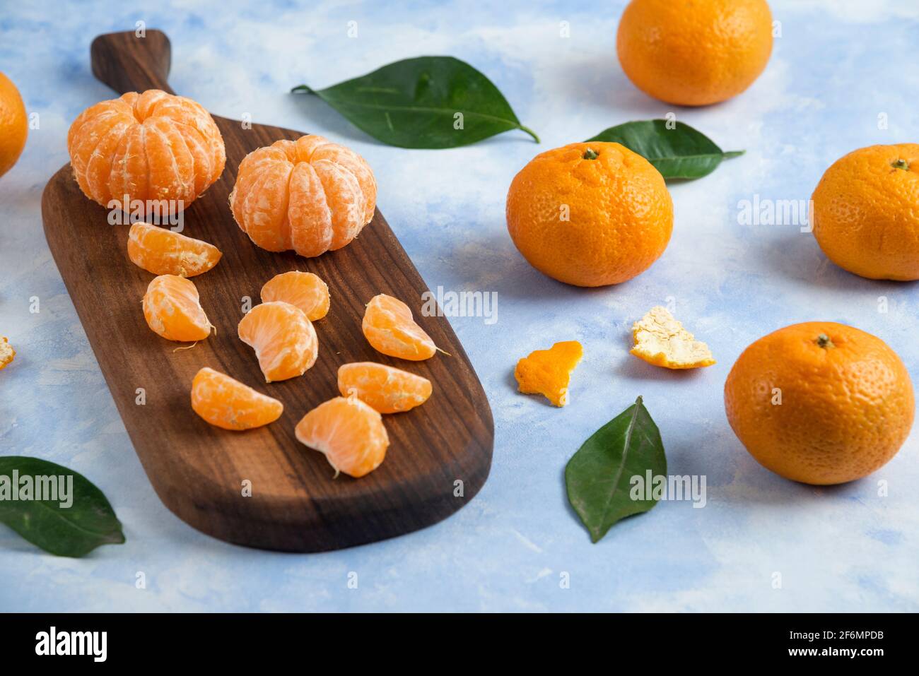 Peeled organic mandarins beside of whole mandarins Stock Photo
