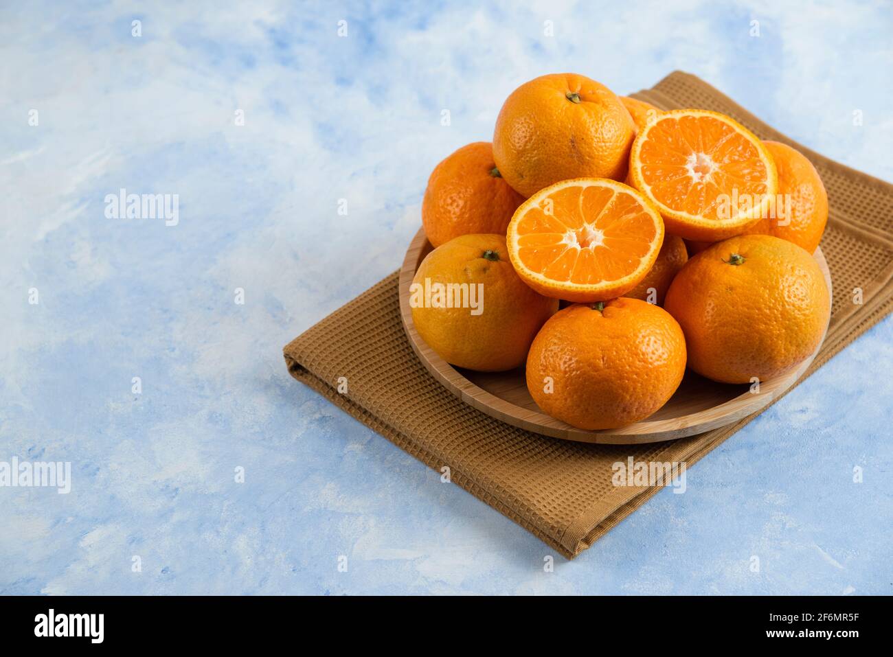 Pile of clementine mandarin n wooden plate over towel Stock Photo