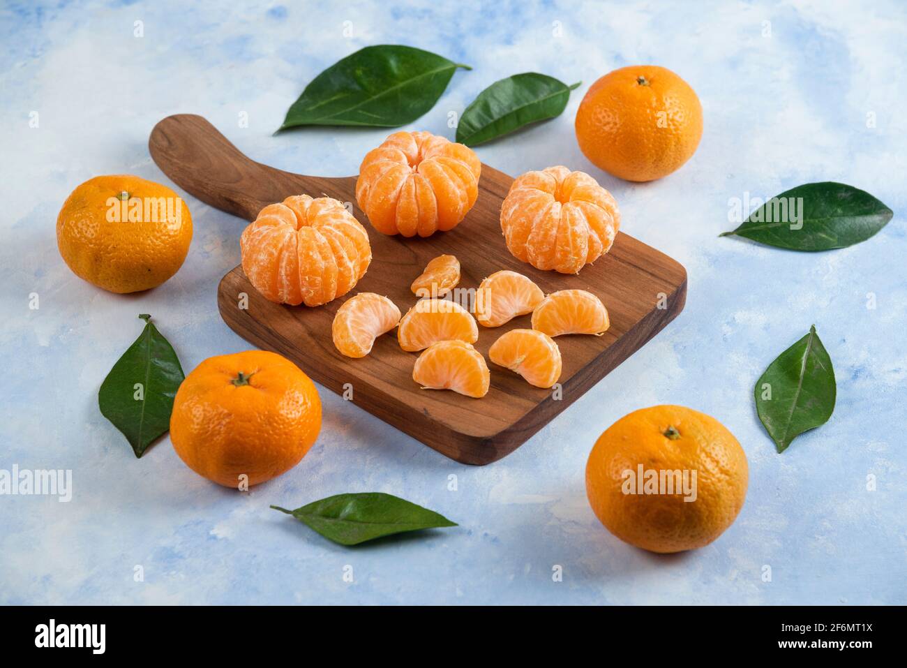 Whole and peeled slice of clementine mandarins. Over wooden board Stock Photo
