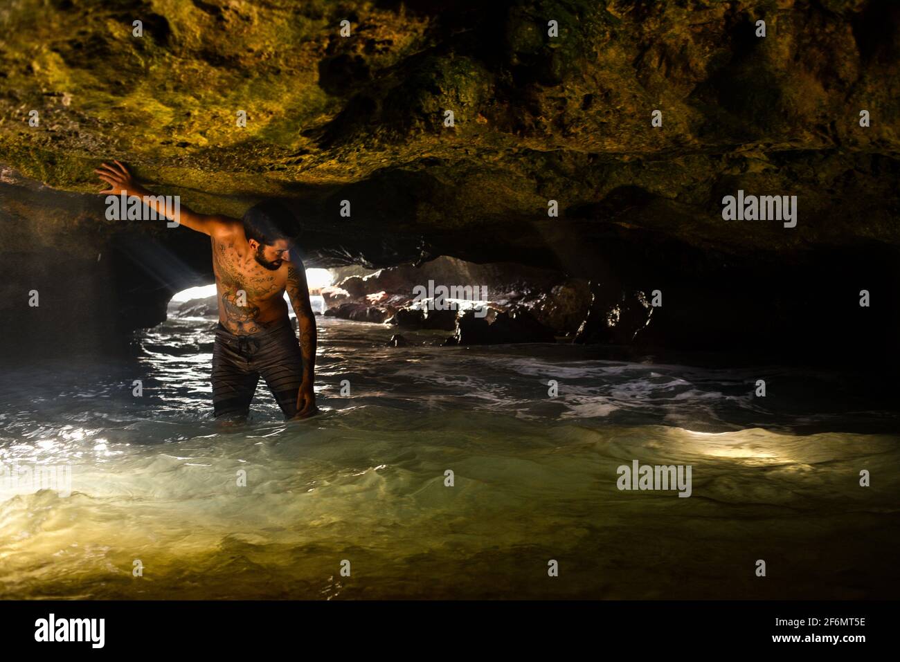 Attractive man with tattoos standing in spectacular Mermaid Caves with