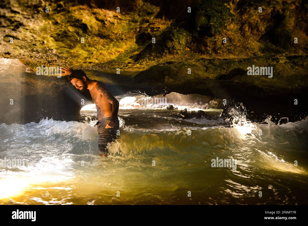 Attractive man with tattoos standing in spectacular Mermaid Caves with