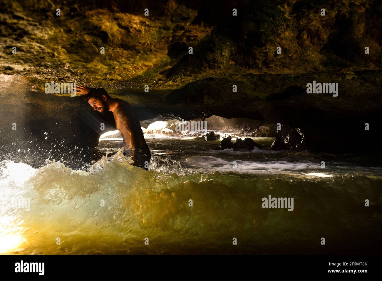 Attractive man with tattoos standing in spectacular Mermaid Caves with