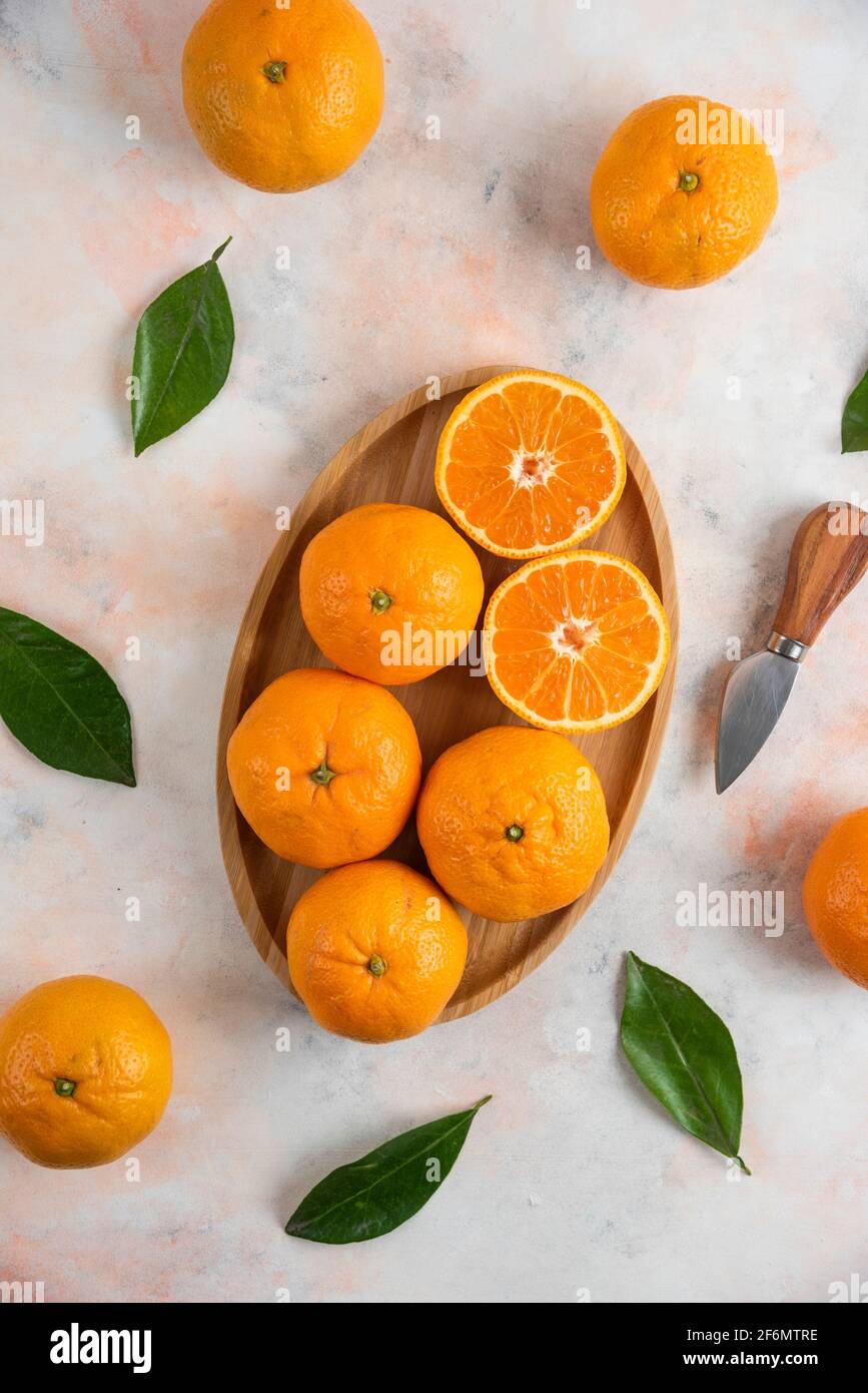 Vertical photo of whole or half cut clementine mandarins over wooden