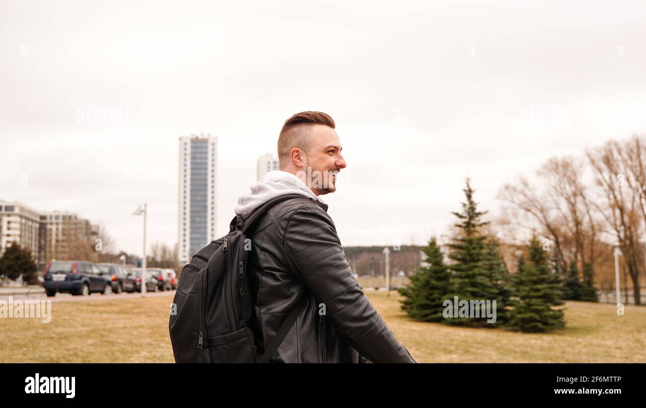 Young man with backpack on his back riding on scooter Stock Photo
