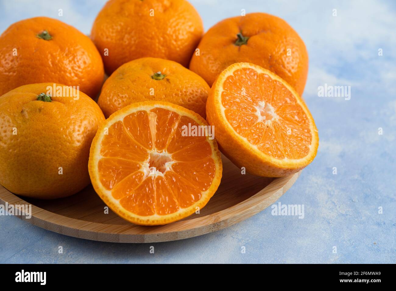 Close up photo of fresh mandarins on wooden plate Stock Photo