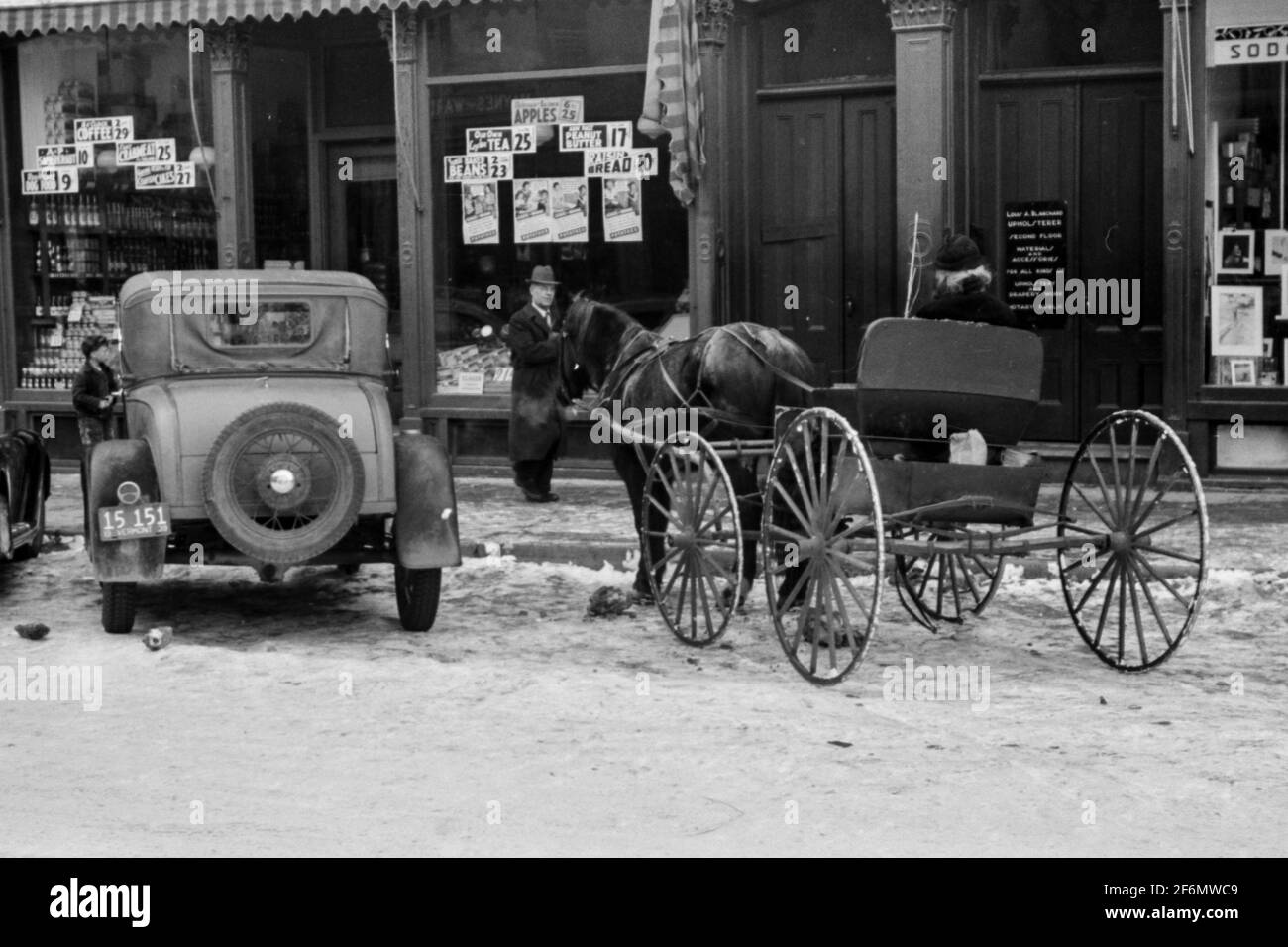 Horse and buggy parked alongside automobiles. Center of Woodstock, Vermont on Saturday afternoon after snow storm. 1939. Stock Photo