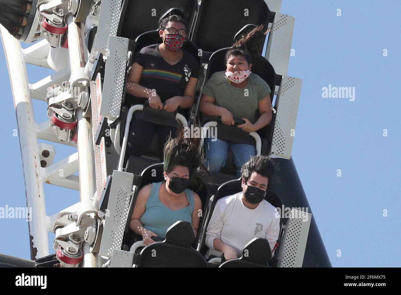 People ride a roller coaster at Six Flags Magic Mountain amusement park on the first day of opening, as the coronavirus disease (COVID-19) continues, in Valencia, California, U.S., April 1, 2021. REUTERS/Lucy Nicholson Stock Photo