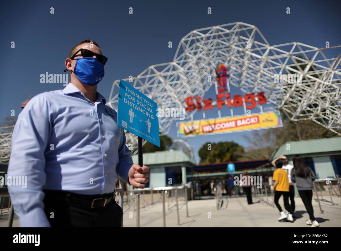 People enter Six Flags Magic Mountain amusement park on the first day of opening, as the coronavirus disease (COVID-19) continues, in Valencia, California, U.S., April 1, 2021. REUTERS/Lucy Nicholson Stock Photo