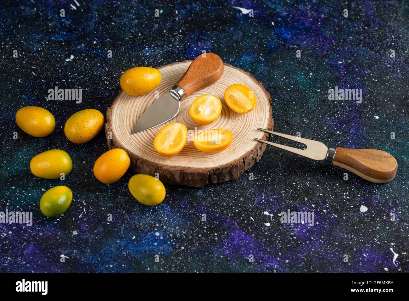 Pile of kumquats whole or half cut over wooden board Stock Photo