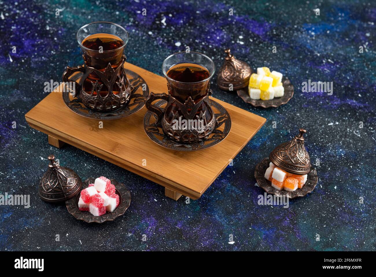 Top view of Two glass tea on wooden board and candies on blue background Stock Photo
