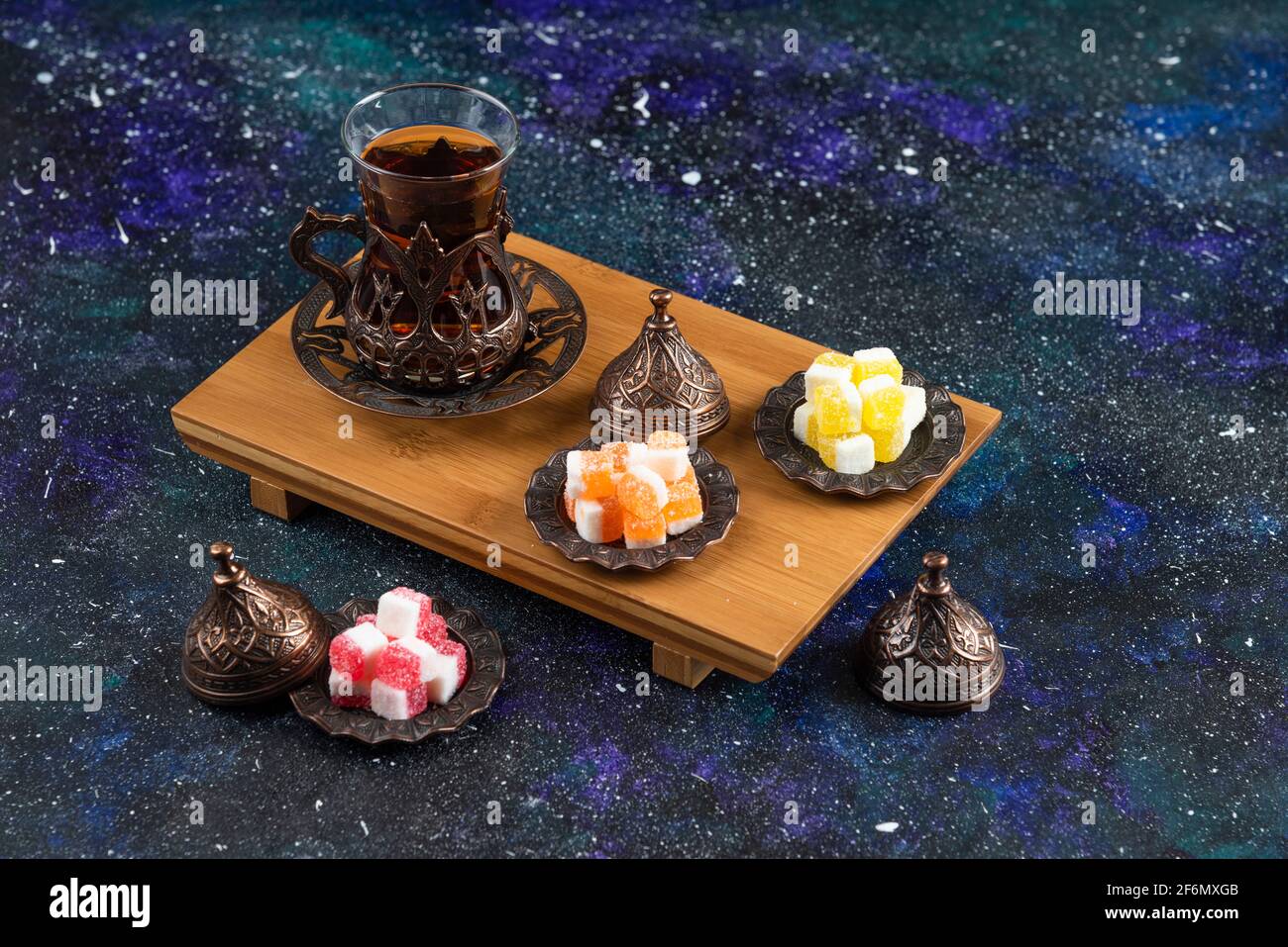 Tea set with Turkish delights on wooden board on colorful background Stock Photo