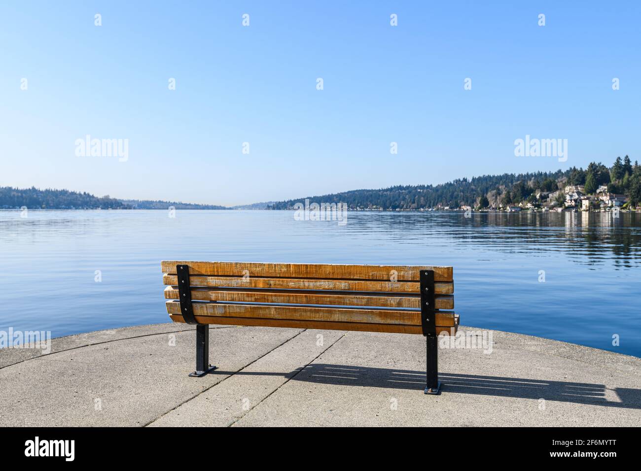 A bench on the edge of Lake Washington on a perfect blue sky morning creates a feeling of solitude and loneliness as it looks out over nothing Stock Photo