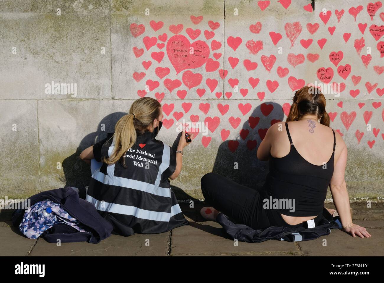 Two volunteers work on the National Covid Memorial Wall drawing hearts in memory of the 127,000 people lost to Covid-19 since last March. Stock Photo