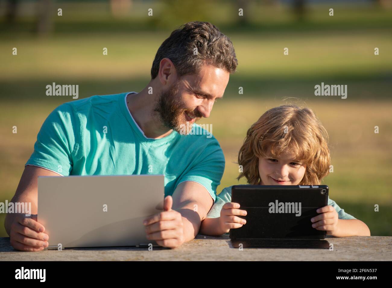 Online learning. Happy father using laptop relax with schooler son ...
