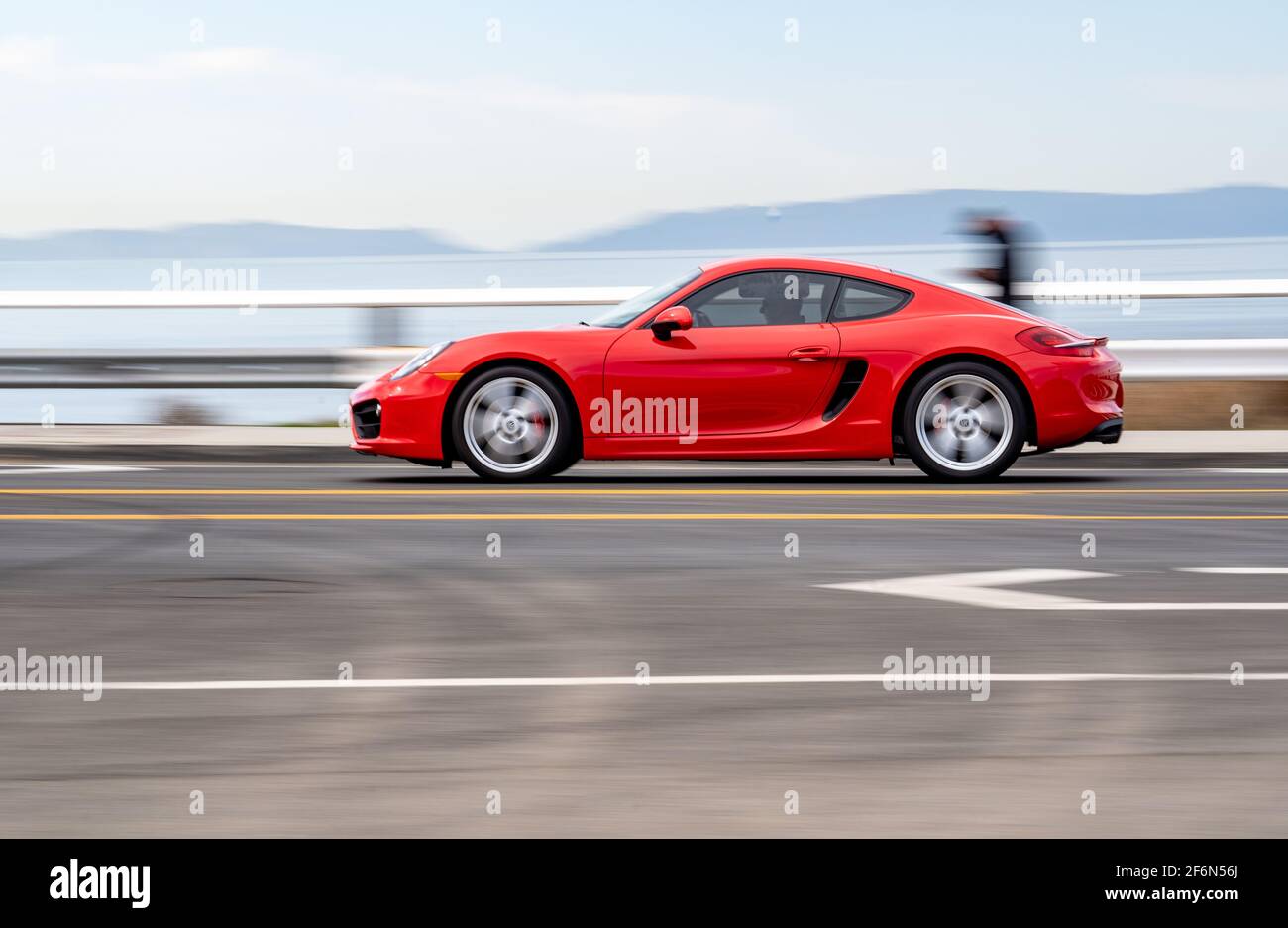 Red Porsche 911 driving along the Southern California coast with motion blur, view of the ocean and Catalina Island in the distance Stock Photo