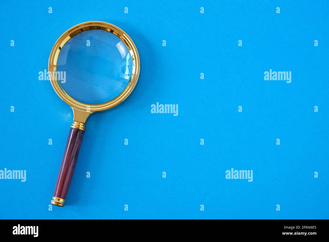 Magnifying glass on a bright blue background Stock Photo - Alamy