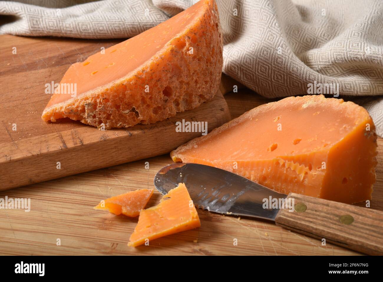 A wedge of gourmet mimolette cheese with a cheese knife on a cutting board Stock Photo