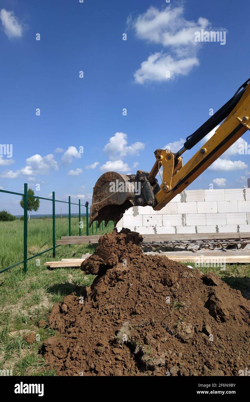 The yellow excavator digs a trench, construction works by means of ...