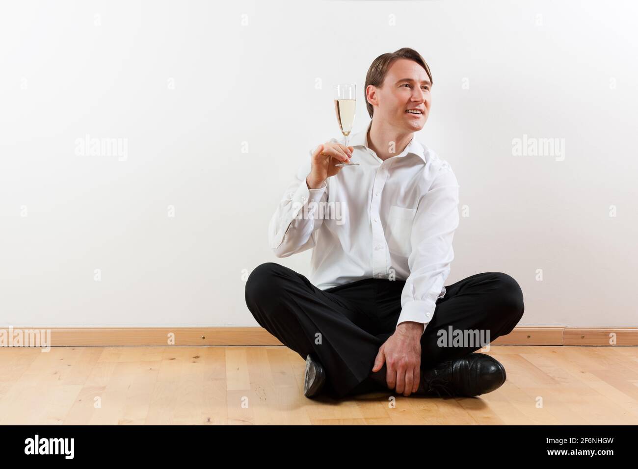 Man sitting cross-legged on the wooden floor of his apartment Stock ...